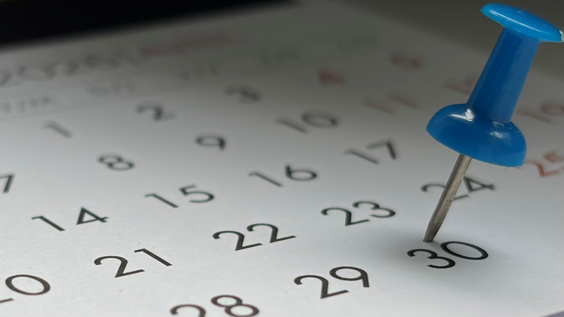 Blue pushpin marking day 30 on a calendar